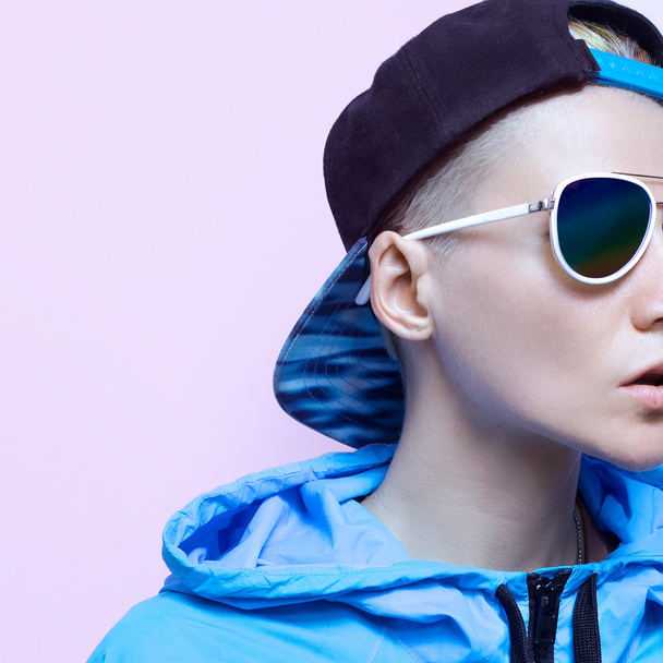 Girl in blue clothes and accessories. Fashion cap and sunglasses - 写真・画像