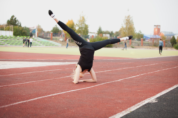 Sports teenage girl in the stadium performs gymnastic exercises - Fotó, kép