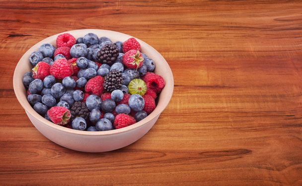 Plate with berries on the wooden table - Photo, image