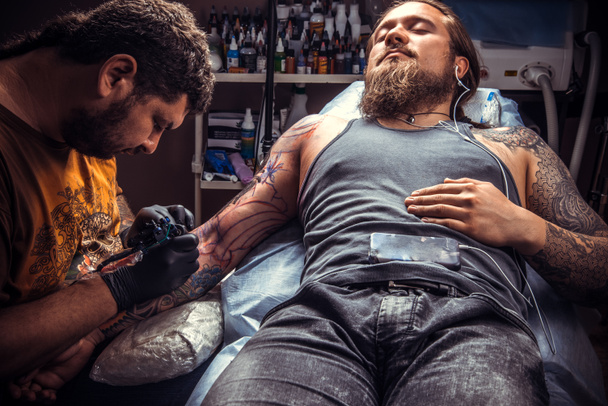 Maestro del tatuaje hace tatuaje en el estudio
 - Foto, imagen