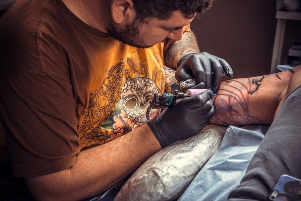 Tattoo master at work in tatoo salon - Photo, Image