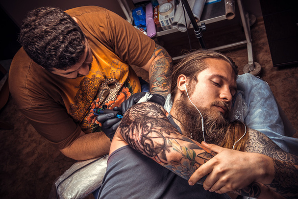 Professional tattooer makes tattoo in tattoo parlor - Photo, Image