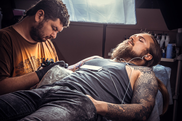 Tatuaggio che mostra il processo di realizzazione di un tatuaggio nel salone del tatuaggio
 - Foto, immagini