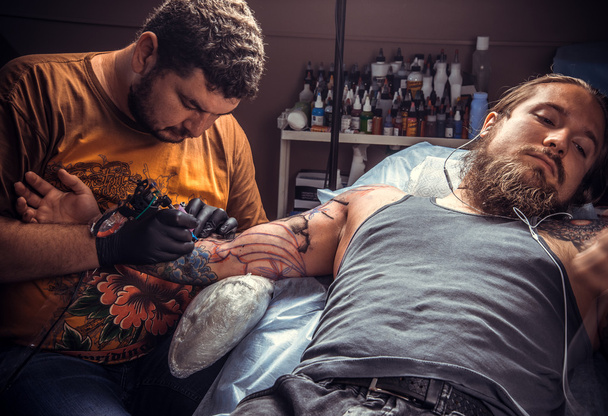 Artista profesional del tatuaje haciendo tatuaje en salón de tatuaje
 - Foto, Imagen