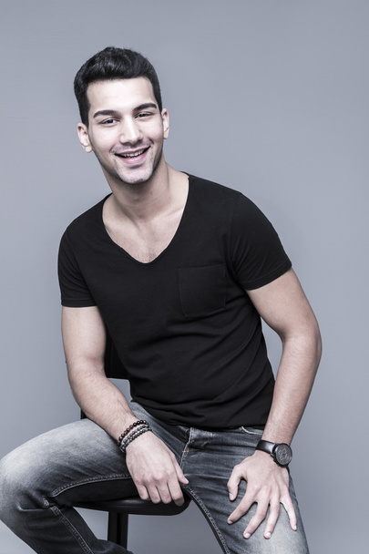 Jeune et beau homme du Moyen-Orient en t-shirt noir sur fond gris, portrait studio
 - Photo, image