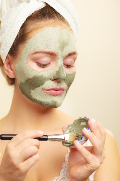Woman applying with brush clay mud mask to her face  - 写真・画像