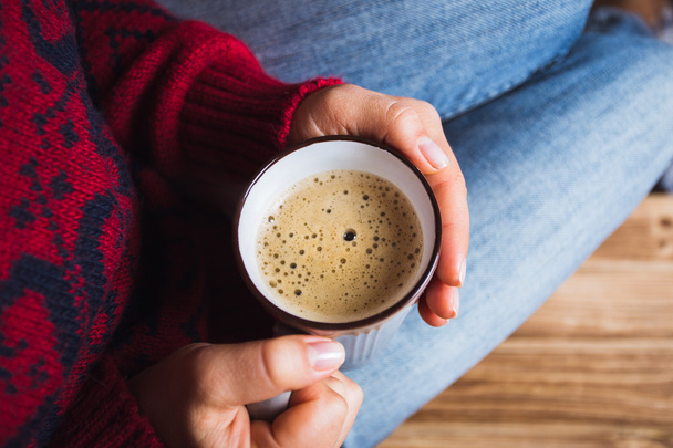 young woman in a red sweater holding a cup of coffee - Foto, Imagen