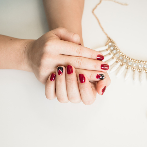 Foto de cerca de unas hermosas manos femeninas con uñas rojas sobre fondo blanco
 - Foto, imagen