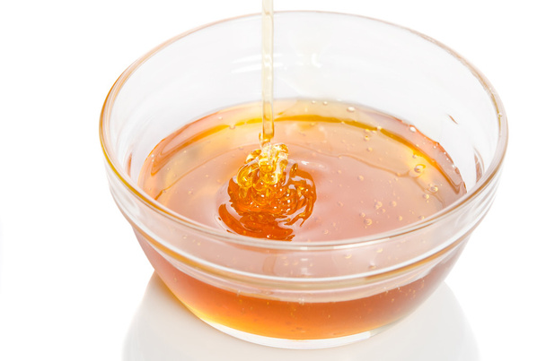 Honey dripping into glass bowl isolated on white background - Fotografie, Obrázek
