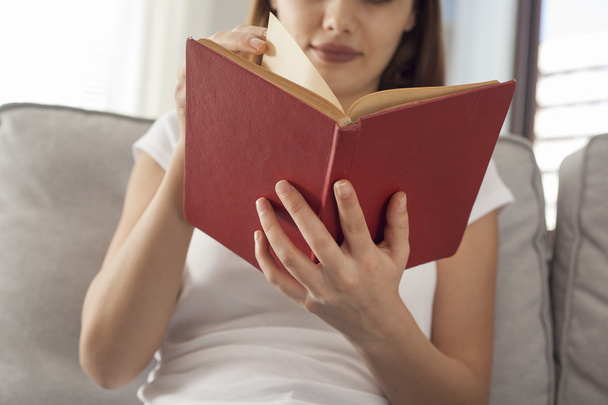 Młoda kobieta, czytanie książki siedzący sofa - Zdjęcie, obraz