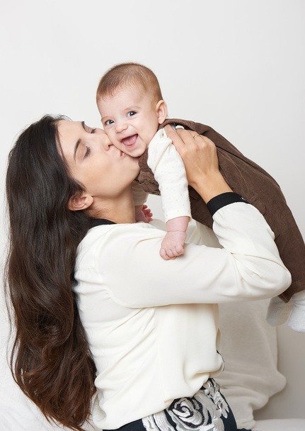 Moeder verhogen van baby- en spelen, gelukkig familieportret op witte achtergrond - Foto, afbeelding