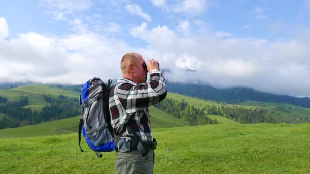 4k. Τουριστική άνθρωπος backpacker στα βουνά μοιάζει με κιάλια. - Πλάνα, βίντεο
