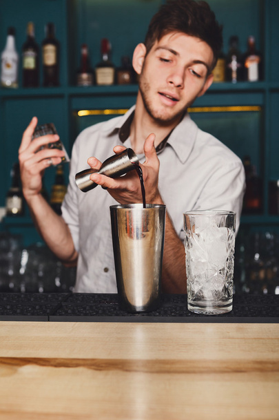 Joven barman guapo vertiendo bebida de cóctel en el vaso
 - Foto, Imagen