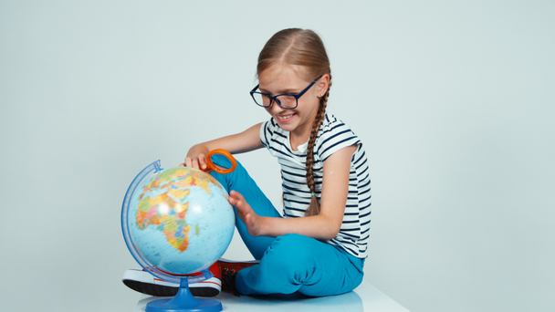 Portrait school girl spinning her globe and looking at camera isolated on white background - Footage, Video