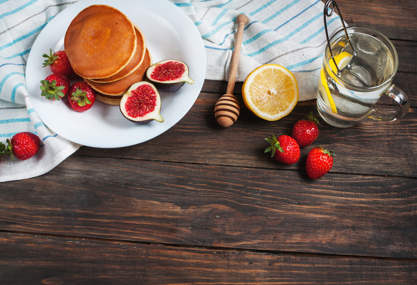 cup of tea and pancakes with figs, strawberries on white plate closeup - Fotó, kép