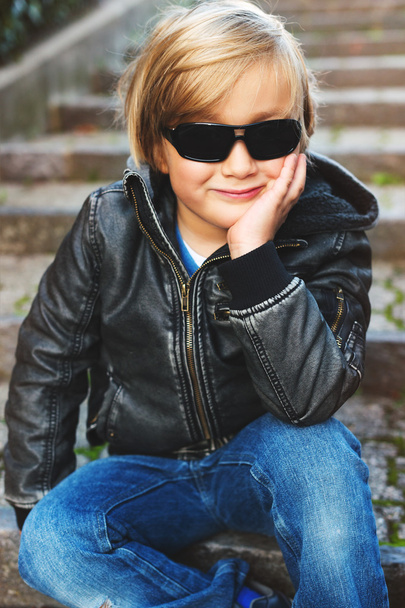 Outdoor Portret van schattige blond jongetje dragen zwarte lederen jas en zonnebril - Foto, afbeelding