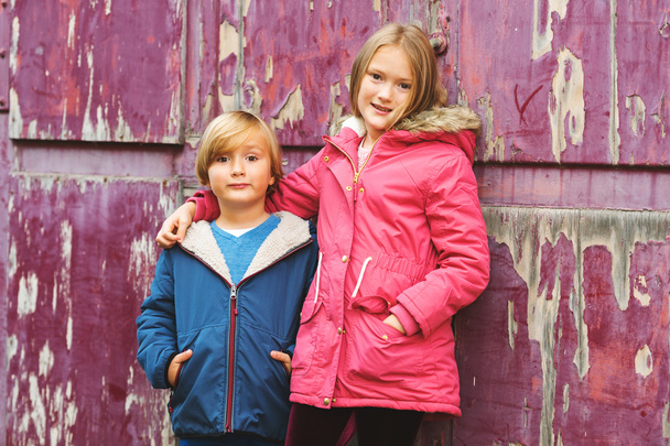 Portrait de deux adorables enfants à l'extérieur, portant des manteaux chauds debout à côté de vieux fond violet
 - Photo, image