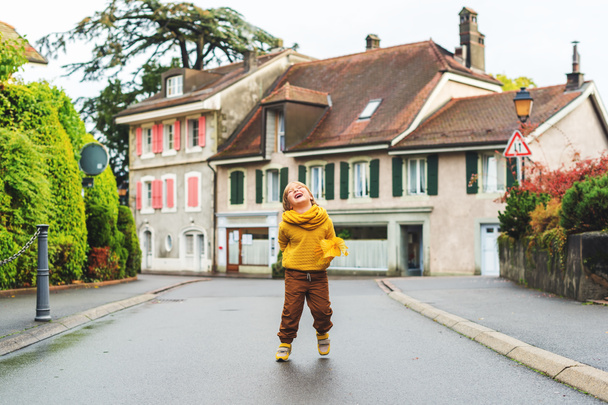 Outdoor-Modeporträt eines entzückenden 5-6 jährigen kleinen blonden Jungen, der gelbes Sweatshirt und Schal trägt  - Foto, Bild