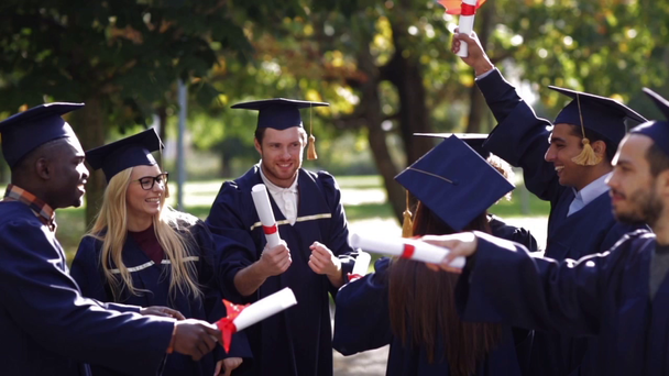 gelukkige studenten in mortierplanken met diploma 's - Video