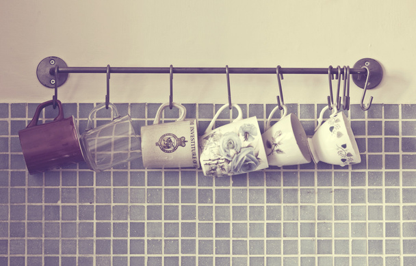 Kaffeetassen hängen an Haken der Küchenwand - Foto, Bild