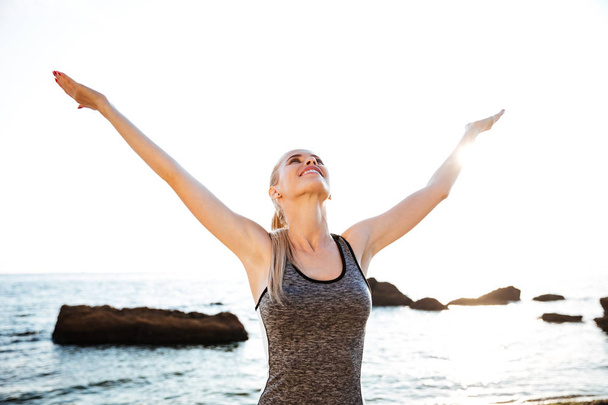 Portrait of a happy fitness woman stretching hands - Фото, изображение