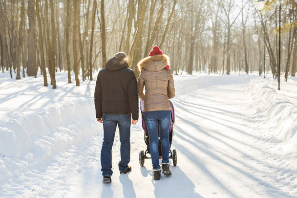 Father and mother with baby carriage in winter forest - Foto, imagen