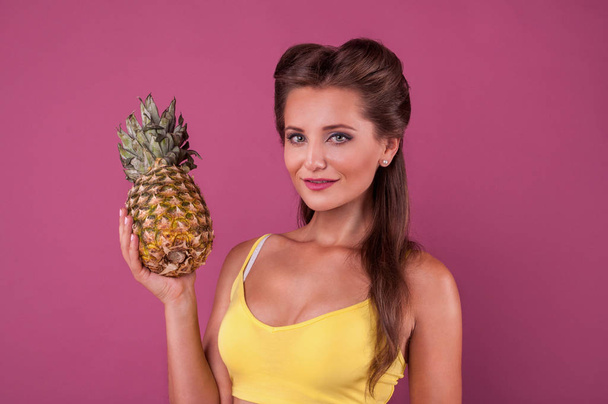 Белая женщина держит ананасовые фрукты улыбаясь здоровой и радостной модели изолированы на розовом фоне
 - Фото, изображение