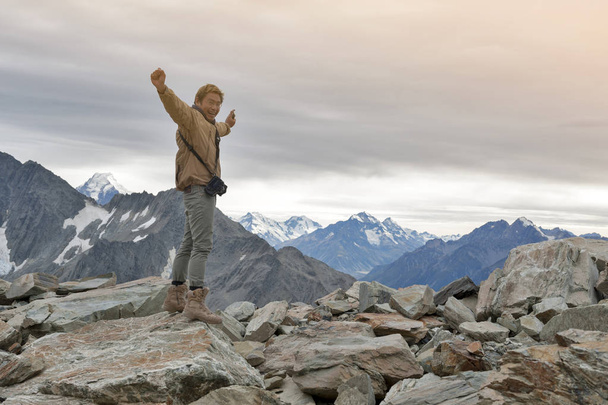 Male model posts at the top of snowcapped mountain peak around Aoraki Mount Cook and Mount Cook National Park - Photo, Image