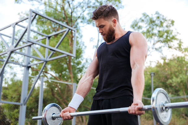 Serious young bearded fitness man lifting barbell - Fotoğraf, Görsel