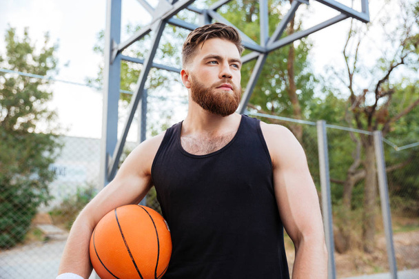 Portrait of a bearded basketball player standing with ball - Photo, Image
