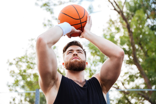 Portrait of a handsome man in sports wear playing basketball - 写真・画像