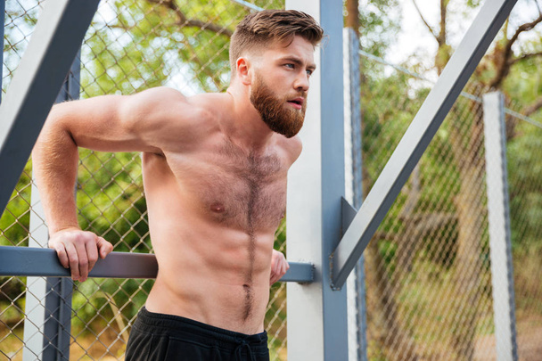 Young concentrated bearded strong man doing sports exercises - Fotoğraf, Görsel