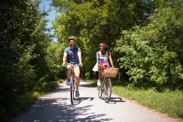 Νεαρό ζευγάρι πολυεθνική έχοντας ένα ποδήλατο βόλτα στη φύση - Φωτογραφία, εικόνα