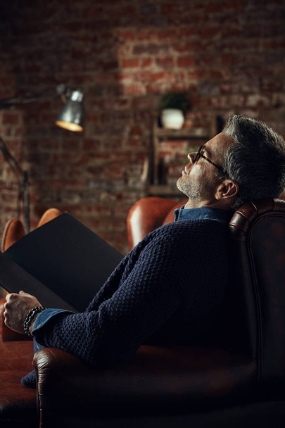 Stylish attractive man with gray hair in studio loft with a book in his hands - Photo, Image