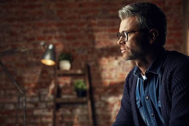 Portrait of handsome businessman with gray hair and glasses in studio loft looking away  - Foto, afbeelding