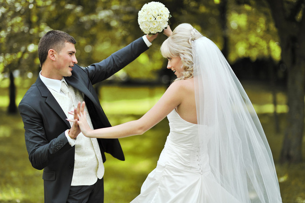 glückliche junge Braut und Bräutigam tanzen zusammen draußen auf ihrem Wir - Foto, Bild