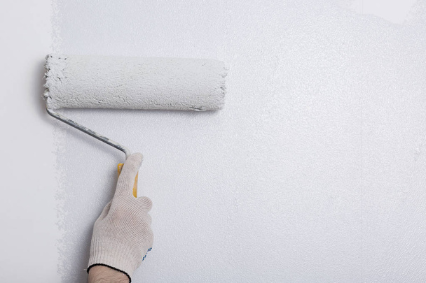 Close up of painter arm painting a wall with paint roller - Foto, immagini