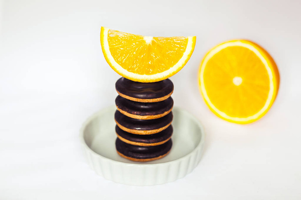 Σωρούς των μπισκότα τσιπ σοκολάτας με πορτοκάλι το πιάτο ψησίματος σε λευκό φόντο. - Φωτογραφία, εικόνα