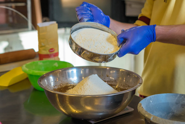Ręce przesiewania mąki w misce - Zdjęcie, obraz