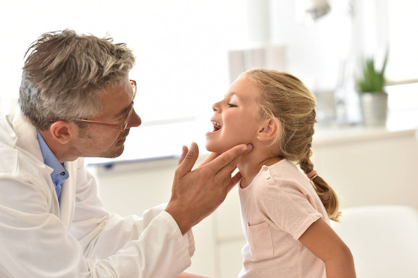 Doctor examining little girl's throat - Foto, afbeelding