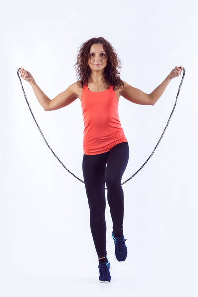 Portrait of muscular young woman exercising with jumping rope on white background. - Photo, Image