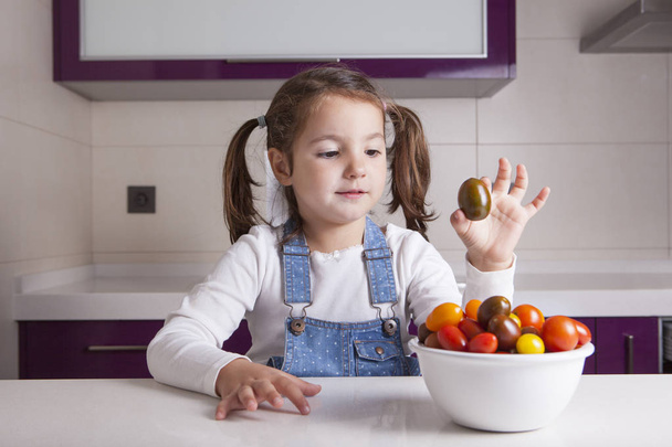 Petite fille à la tomate cerise à la main
 - Photo, image