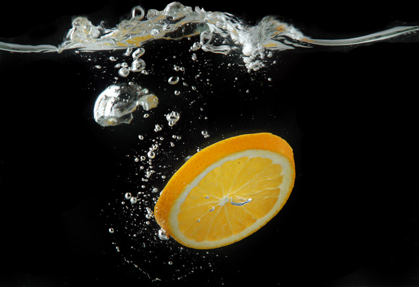 Slice of orange in the water on black background - Zdjęcie, obraz