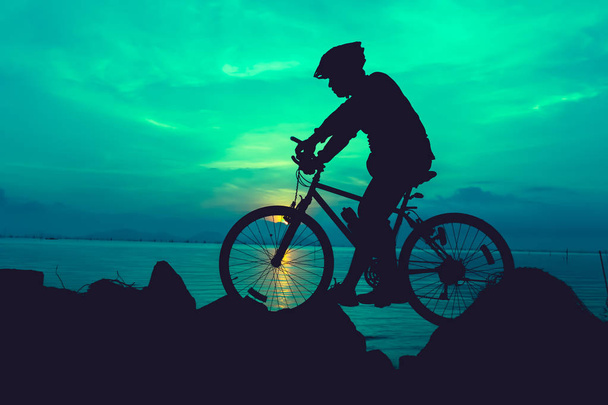 Gezonde levensstijl. Silhouet van de fietser met de fiets op se - Foto, afbeelding