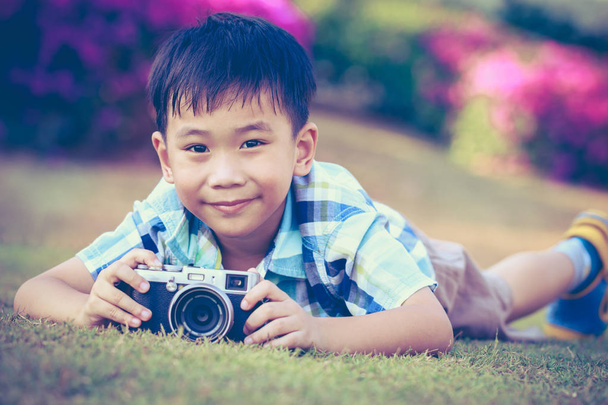 少年が公園で自然を探検し、カメラで写真を撮影.  - 写真・画像