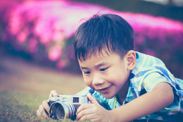 Niño tomando fotos por cámara, explorando la naturaleza en el parque. Tono vintage
. - Foto, imagen