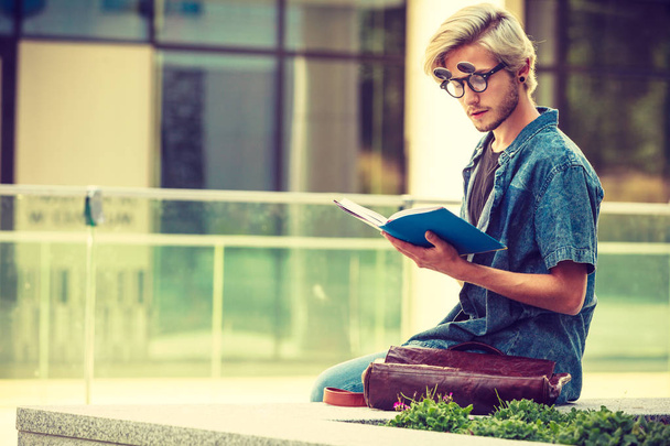 Hipster guy holding notebook sitting on ledge - Φωτογραφία, εικόνα
