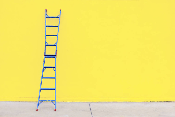 The blue steel ladder with the yellow concrete  wall  - Photo, Image