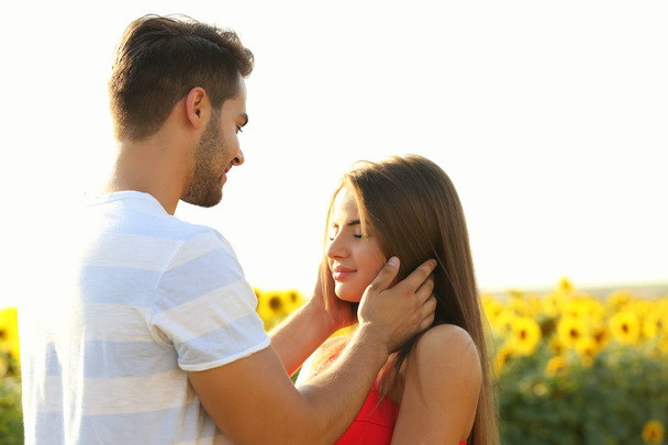 Romantic young couple embracing in a field of sunflowers - Photo, Image