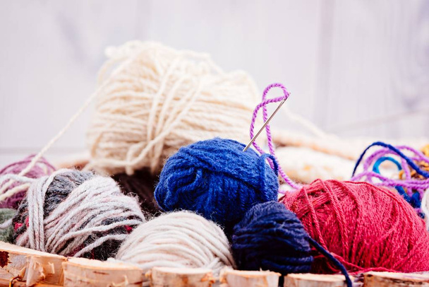 Bolas de lana coloridas y agujas en cesta de madera
 - Foto, imagen